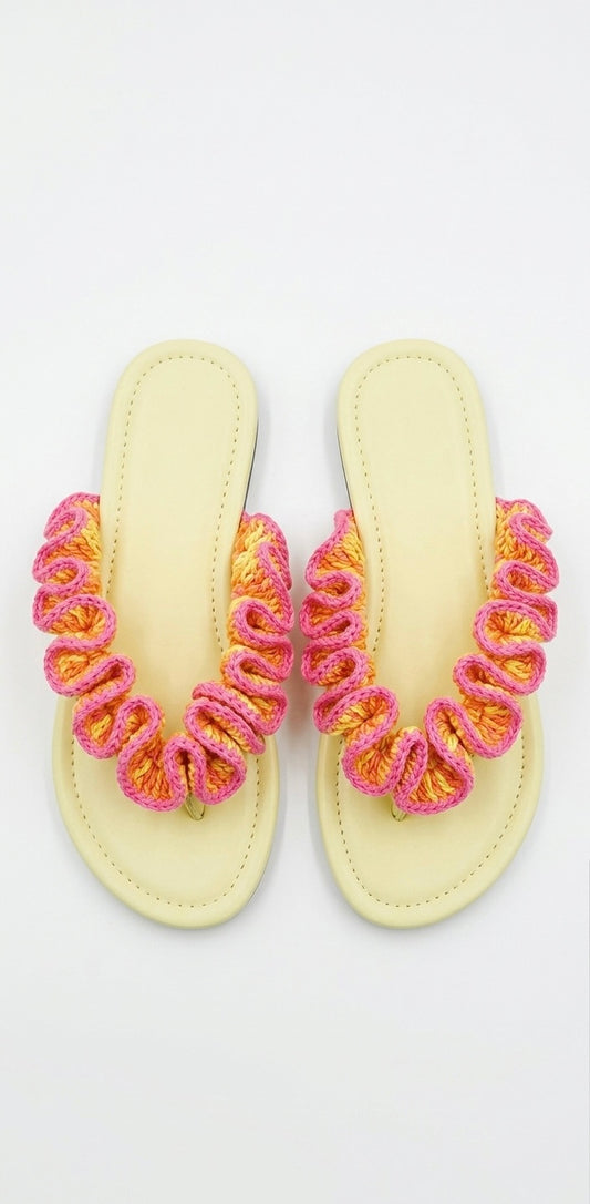Pair of yellow sandals with pink and orange ruffled crochet straps on a white background