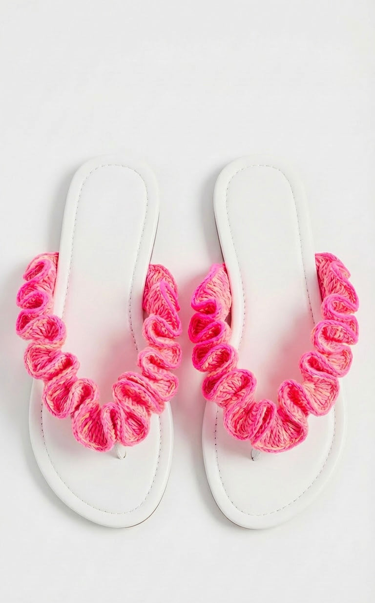 White sandals with neon pink crochet ruffled straps on a white background