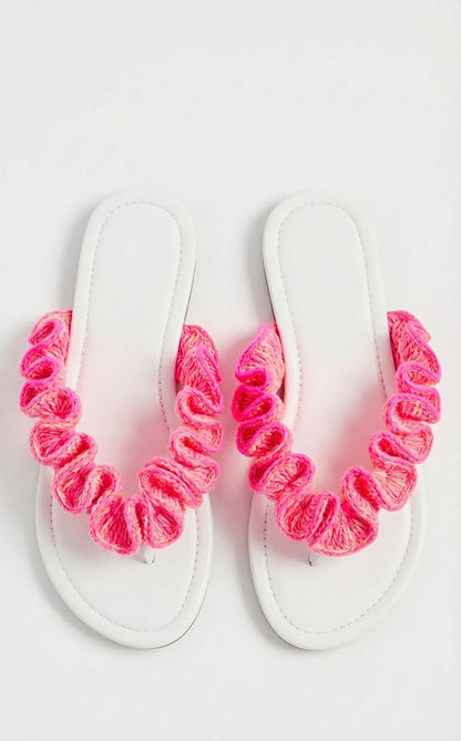 White sandals with neon pink crochet ruffled straps on a white background
