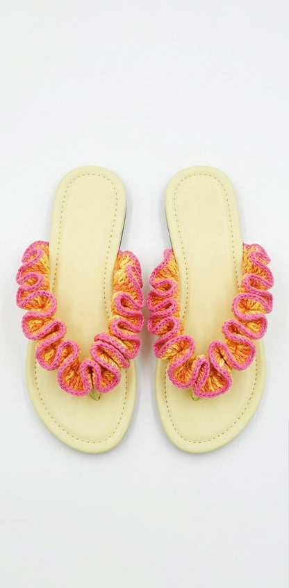 Pair of yellow sandals with pink and orange ruffled crochet straps on a white background