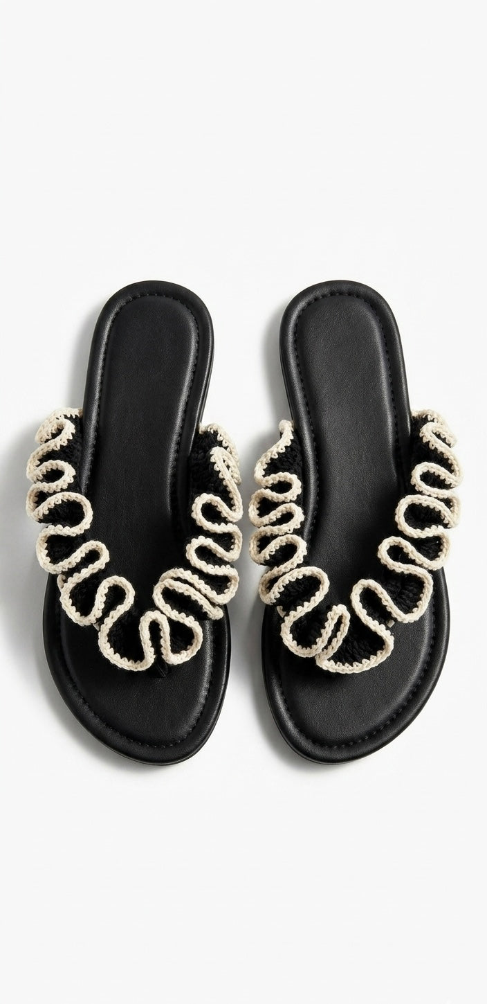 Black sandals with black and white crochet  ruffles on a white background