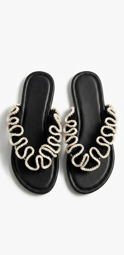 Black sandals with black and white crochet  ruffles on a white background