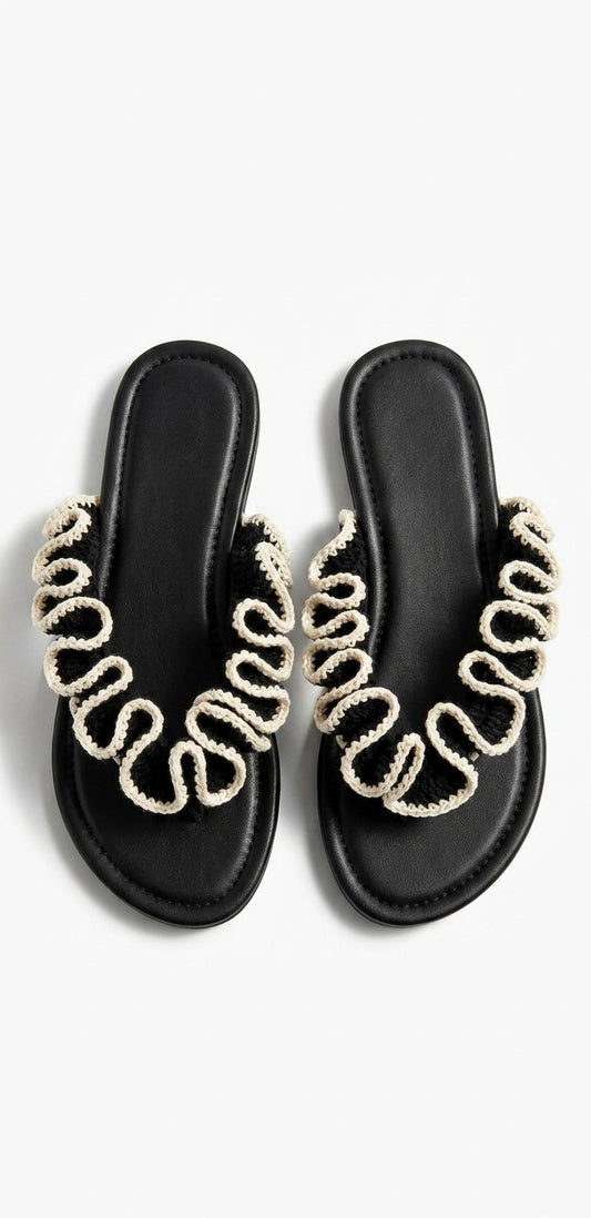 Black sandals with black and white crochet  ruffles on a white background