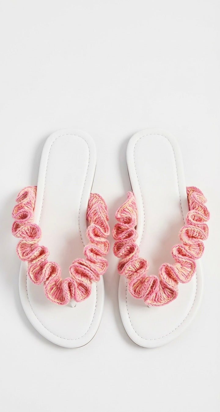 White sandals with pink crochet ruffled straps on a white background